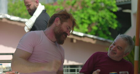 Obraz premium Elderly man dancing joyfully with a younger man in a casual outdoor barbecue setting, highlighting laughter, happiness, and intergenerational bonding through movement