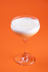 refreshing drink with foam and contreau and lemon on orange background