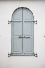 A grey shuttered window on a white building.