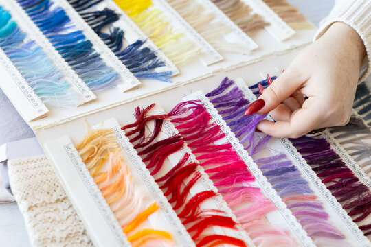 Designer selecting fabric color samples from palette book on table. Creativity, craftsmanship, and fashion design process in textile studio.