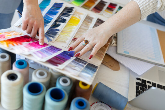 Team of designers analyzing fabric color palette samples in creative workspace. Fashion design planning, collaboration, and teamwork.