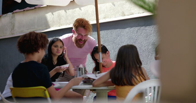 Diverse group of friends sharing a joyful meal outdoors under an umbrella, highlighting connection, togetherness, and vibrant social interaction at a casual gathering