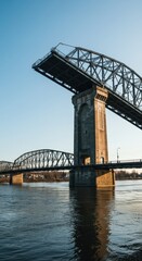 Fototapeta premium Massive metal drawbridge structure crosses a wide, flowing river under a bright sky, emphasizing engineering and transport infrastructure, navigation, below, flow