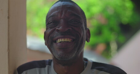 Close-up of a mature man smiling warmly outdoors, highlighting genuine joy and character, African...
