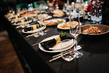 Elegant banquet table setting with black napkins and gourmet dishes in restaurant