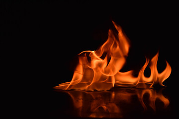 A captivating image of fire with multiple tongues of flame rising and intertwining, glowing in...