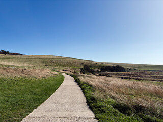 Winding gravel path through rolling hills under a clear blue sky in East Sussex Seven Sisters area