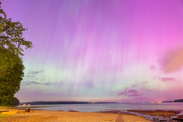 Rare northern lights over Flensburg Baltic Sea beach glowing in pink and green night sky