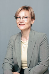 Portrait of happy woman. Confident, successful mature woman on light gray background. Looking at camera. High quality photo