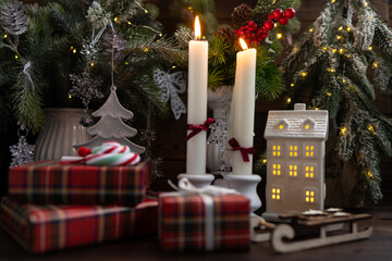New Year's table setting with white candles and an elegant Christmas tree in the background. A festive and New Year's atmosphere.