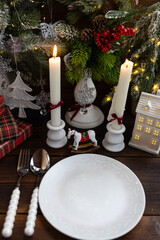 New Year's table setting with white candles and an elegant Christmas tree in the background. A festive and New Year's atmosphere.