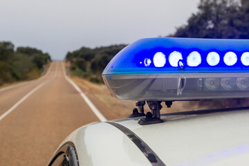 Fototapeta premium Blue Police Light Bar. Close-up on White Roof with Blurred Road Extending to the Horizon.