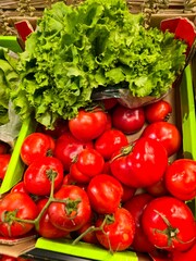 Fresh Red Tomatoes and Crisp Green Lettuce Displayed Together in a Cardboard Box at a Farmer's Market or Grocery Store