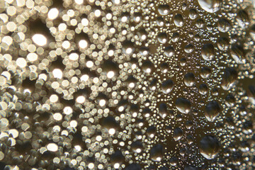 Macro view of rain drops on glass surface. Transparent water, streaks, blurred urban or nature background, abstract and cinematic look for advertising, design, or social media.