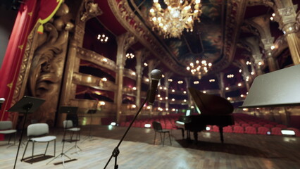 Naklejka premium In a lavish concert hall, a grand piano sits in the spotlight. Rows of empty seats await an audience, while warm glow of chandeliers create an inviting atmosphere.