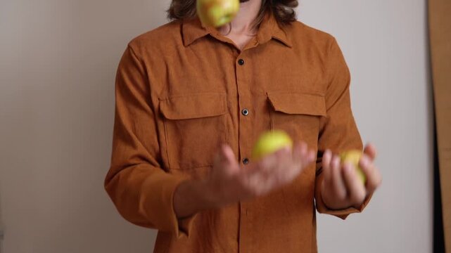 Slow-motion video of a person juggling three red apples on a clean white background.