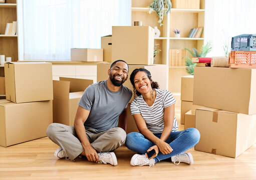 Portrait of a young couple unpacking, moving in and relocation to a new apartment, happy young couple family new beginning sitting on the floor
