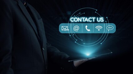 A professional businessman stands holding a tablet, featuring a digital contact interface. The image represents modern communication and networking technology in a business environment. Qubit - Powered by Adobe
