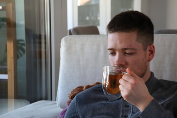 man drinking cup of tea on couch