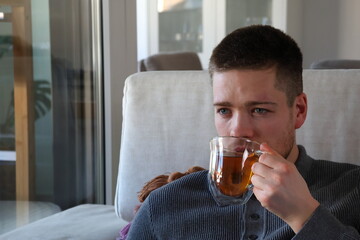 man drinking cup of tea on couch