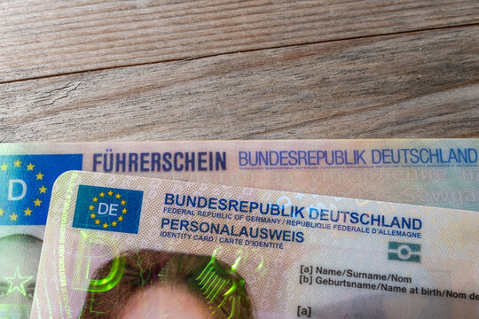 German ID card and driver&rsquo;s license in hand, EU flag, Modern European driving permit, identification and travel, personal card and license, EU citizen travel, mobility documents