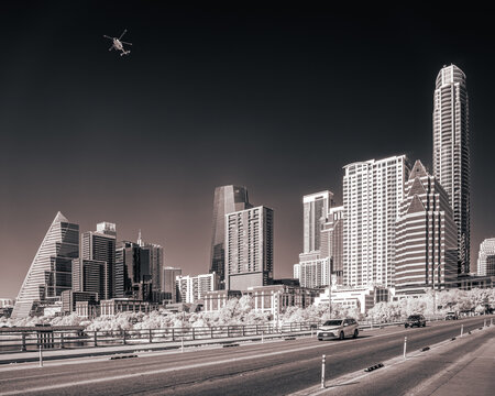 Artistic infrared black and white capture of Austin&rsquo;s skyline, where classic and modern architecture meet in perfect balance, framed by glowing foliage and a dark, dramatic atmosphere.