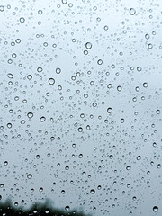 Rain drops close up on window glass outdoors. Summer rain. Texture of water in heavy rain in the street. Macro. Rain drop on car window over blurred nature background, rainy season background idea