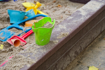 Close view of sandbox with bright plastic toys in soft sand