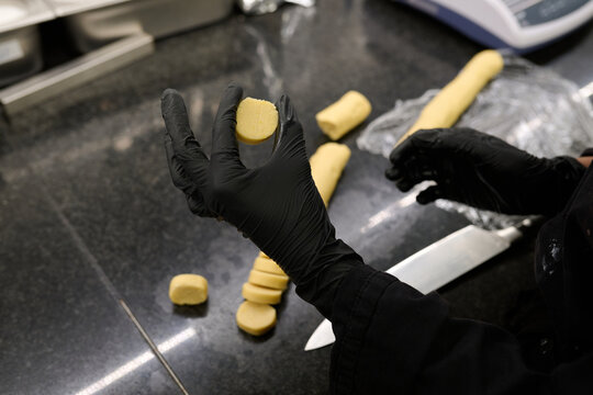 Skilled chef in black gloves is preparing dough on a sleek countertop, showcasing culinary techniques and precision in the kitchen environment