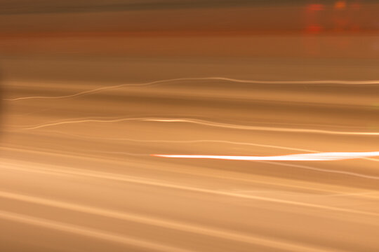 Abstract photo of golden light streaks and motion blur, creating a smooth dynamic background. Represents speed, technology, futuristic energy, and modern design.
