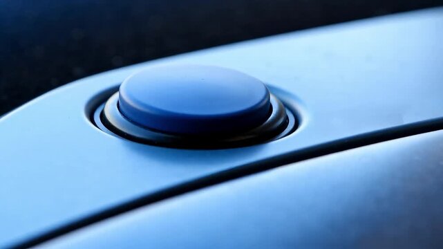 Close-up of a round blue button being pressed by a finger