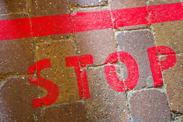 Red stop marking painted along curb on sidewalk path