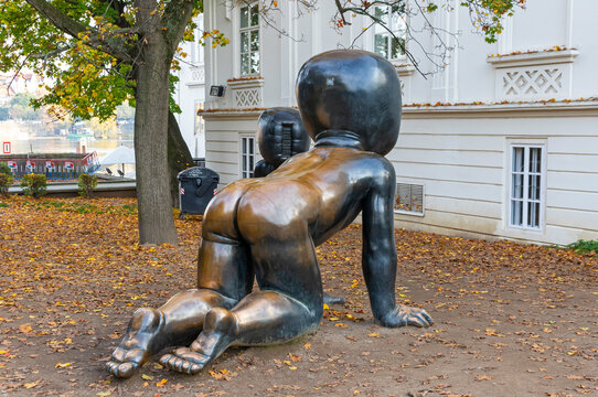 Crawling Babies sculptures (Czech: Miminka) by artist David Cerny at Kampa Museum. Faceless bronze toddlers with barcode faces crawl among autumn leaves