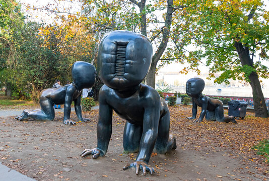 Crawling Babies sculptures (Czech: Miminka) by artist David Cerny at Kampa Museum. Faceless bronze toddlers with barcode faces crawl among autumn leaves