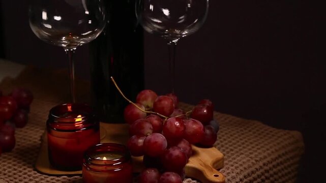 Still life two wine glasses with grapes bunch near romantic aroma burning flame fire candles on a table on dark backround. Decor concept of Christmas holiday celebration with fresh sweet ripe dessert