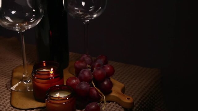 Still life two wine glasses with grapes bunch near romantic aroma burning flame fire candles on a table on dark backround. Decor concept of Christmas holiday celebration with fresh sweet ripe dessert