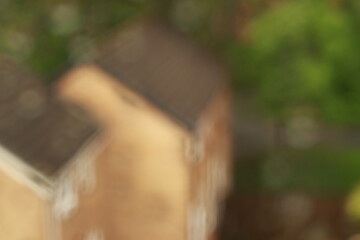 Artistic photo of raindrops on a window with a soft, blurred view of a cozy house in the background. Atmospheric and tranquil mood.