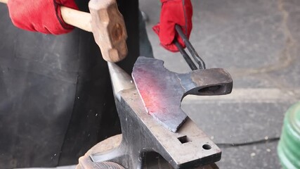 Gloves protect hand of artisan as he shapes glowing axes on an anvil using hammer - Powered by Adobe