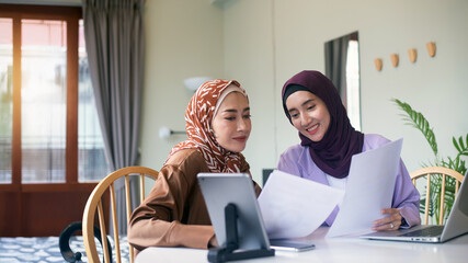 Attractive young Muslim woman is using her laptop and smartphone to plan her business structure and sell products online, shopping online, Banner Online, Copy space.