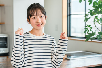 Elementary and junior high school girls (border casual) pumping their fists in the kitchen or dining room at home
