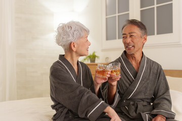 寝室で晩酌するシニア夫婦（お酒・飲酒）