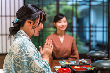 A woman in a yukata eating dinner at a hot spring inn, in-room dining, or in a traditional Japanese...