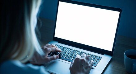 Young woman working late on her laptop in a dimly lit room with a cup of coffee	