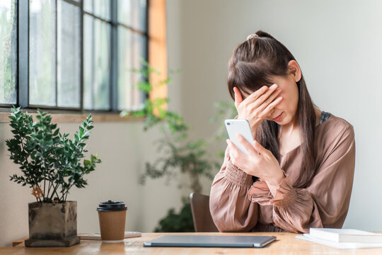 A middle-aged businesswoman is shocked while looking at her smartphone in a cafe
