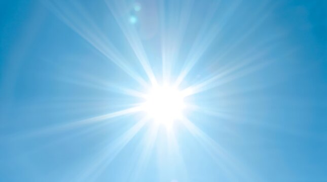 Bright sun shining in a clear blue sky with sunbeams and lens flare effect