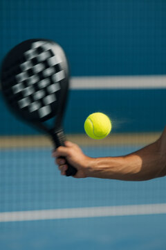 yellow padel ball flying in motion before being hit by racket on court