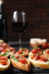 Delicious bruschettas with prosciutto and red wine served on black table, closeup