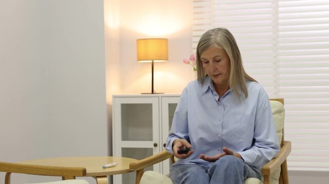 Diabetes. Woman checking blood sugar level with lancet pen and glucometer on armchair indoors, camera moving forward