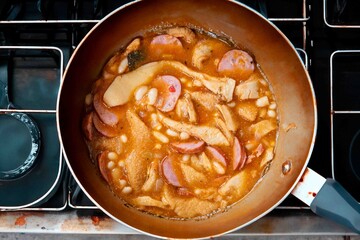 A classic Brazilian dish known as dobradinha, prepared with beef tripe, white beans, and tropical spices, served with traditional farofa made with toasted cassava flour.
