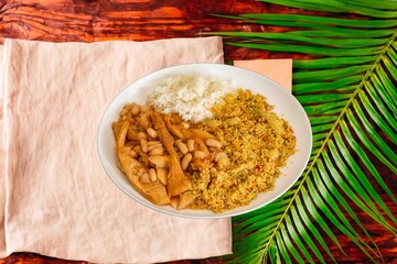 A classic Brazilian dish known as dobradinha, prepared with beef tripe, white beans, and tropical spices, served with traditional farofa made with toasted cassava flour.